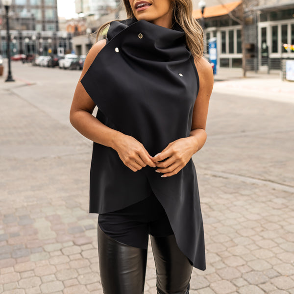 En kvinde iført et sort på sort look med veganske leggings i imiteret læder og en asymmetrisk vest fra Malaika New York. En perfekt pasform til din kapselgarderobe