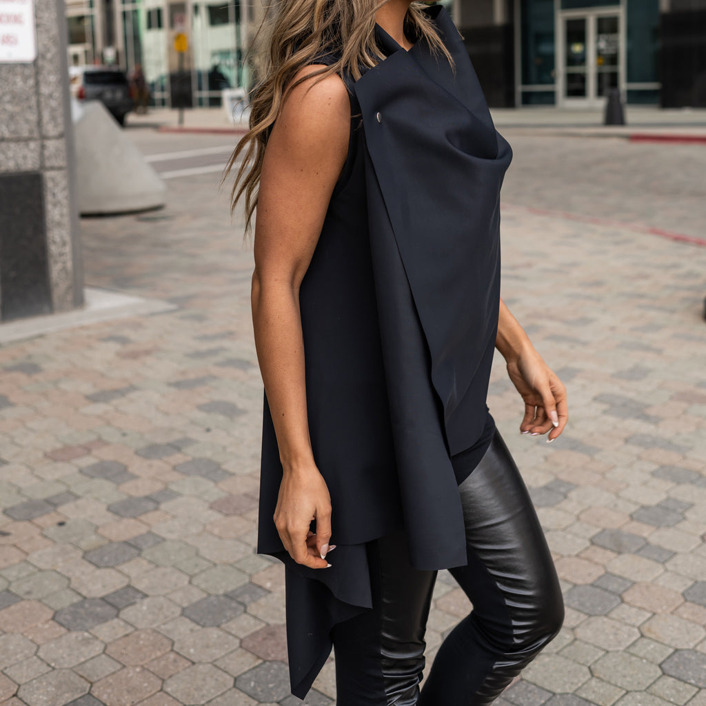 A woman wearing an asymmetrical black vest from ECONYL fibers. A black on black look by Malaika New York