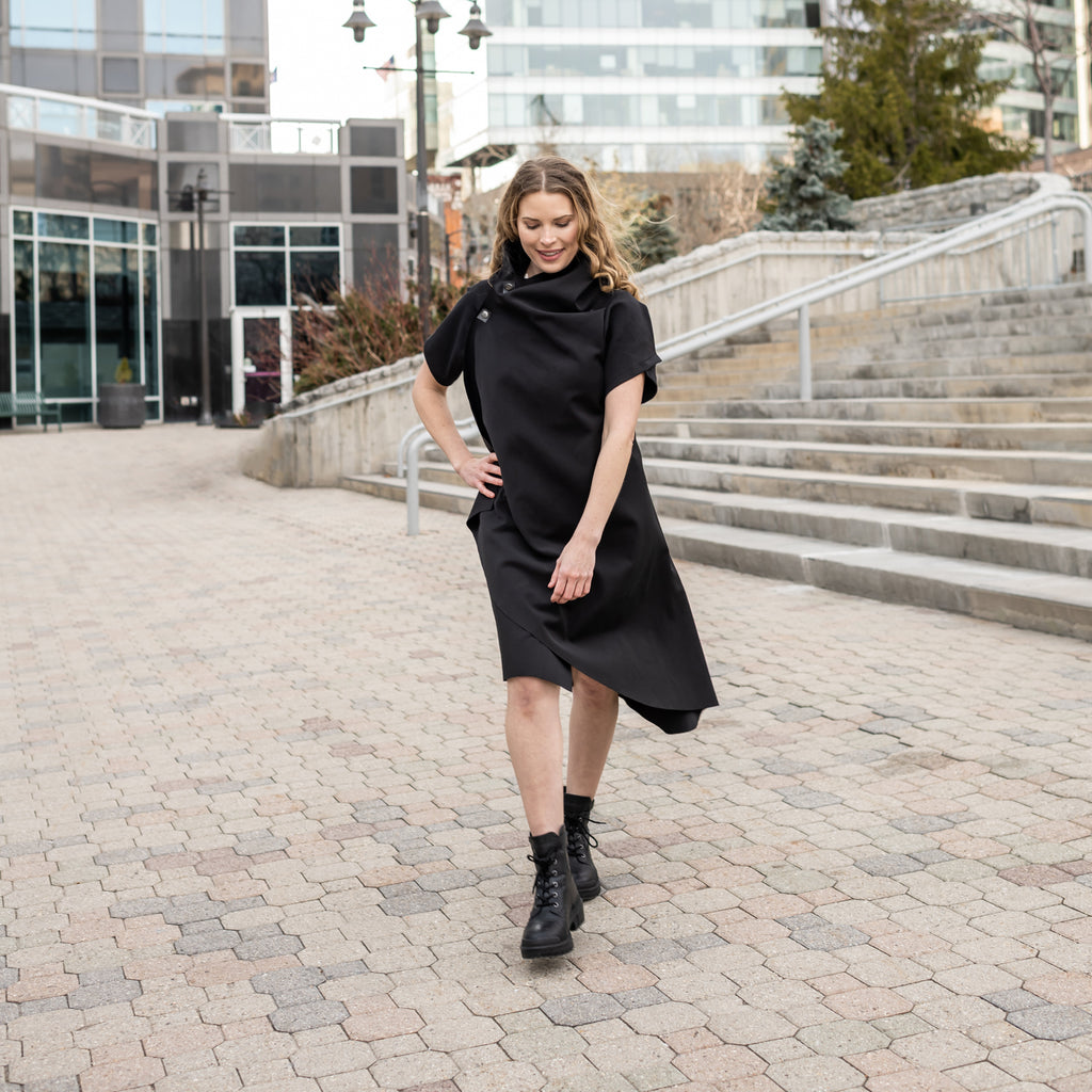 A woman wearing a black knee-length shift dress by Malaika New York