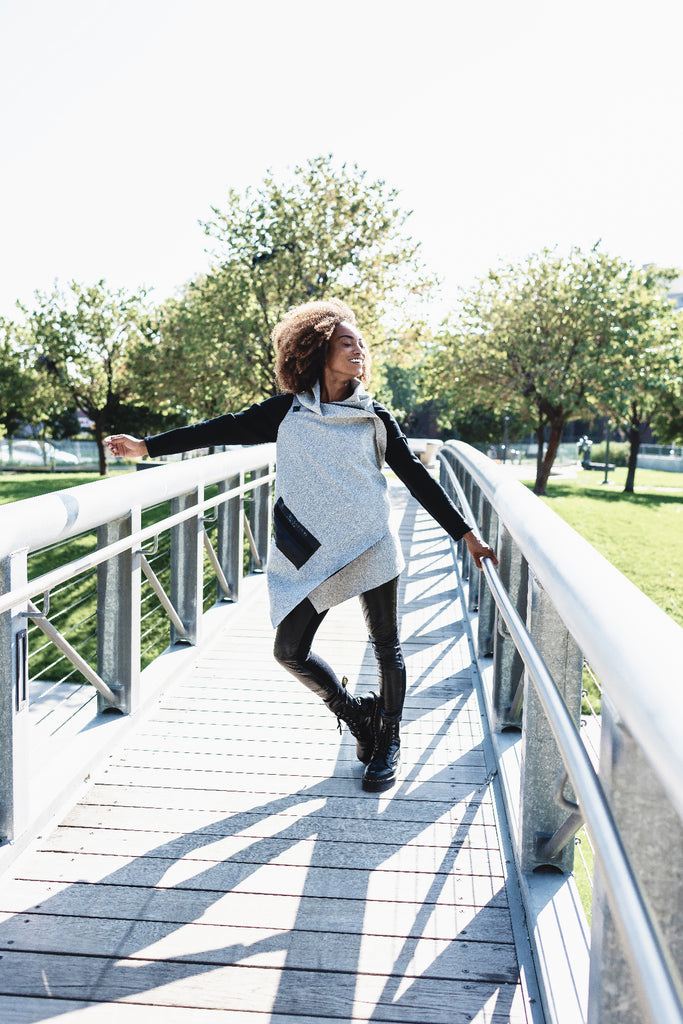 A woman wearing a grey organic cotton sustainable cardigan with black sleeves by Malaika New York