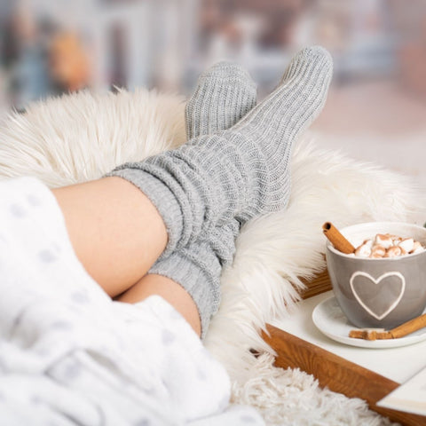 person on sofa wearing thick cosy socks with hot chocolate drink to the side