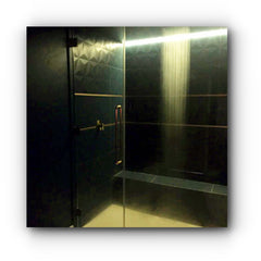 black tiled shower room with copper handles on unframed glass shower door