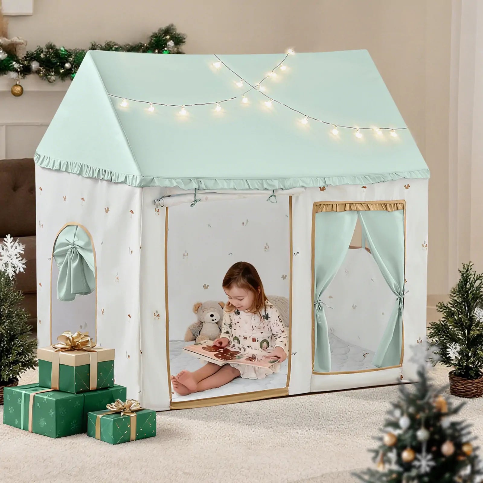 a little girl wearing cute dress is reading a book inside her green play tent next to Christmas trees and gift boxes