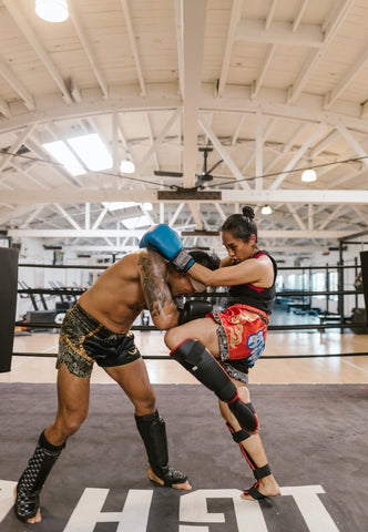 Woman and Man Practicing Muay Thai Sparring in Ring