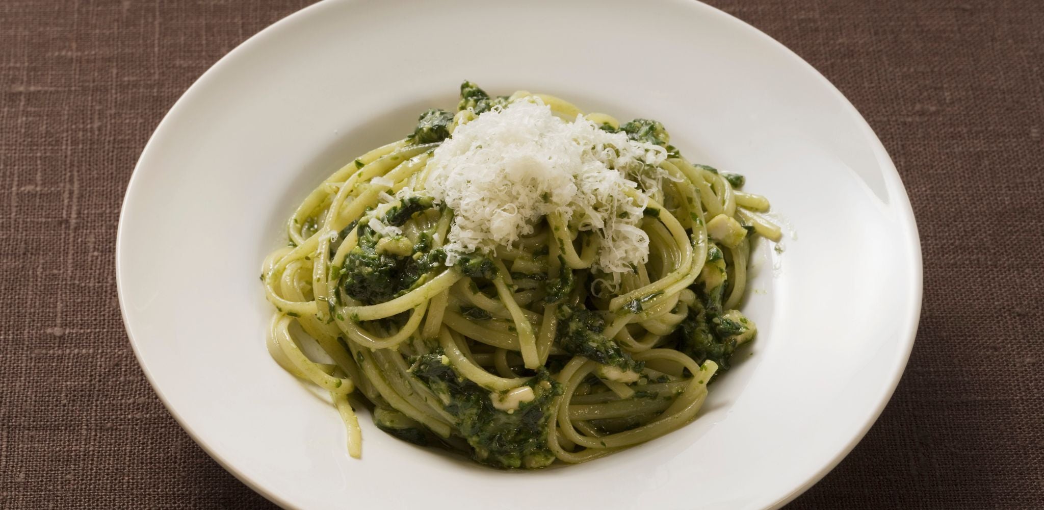 Spaghetti with Pesto and parmesan cheese, in a white bowl