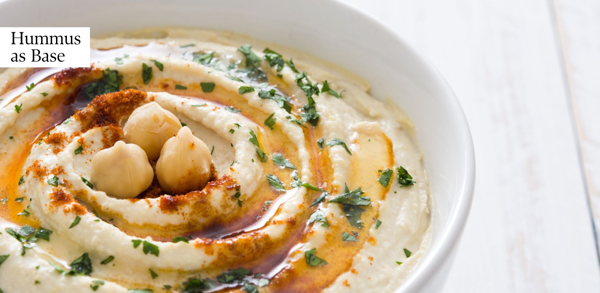 Hummus in a white bowl, with extra virgin olive oil and toasted chickpeas