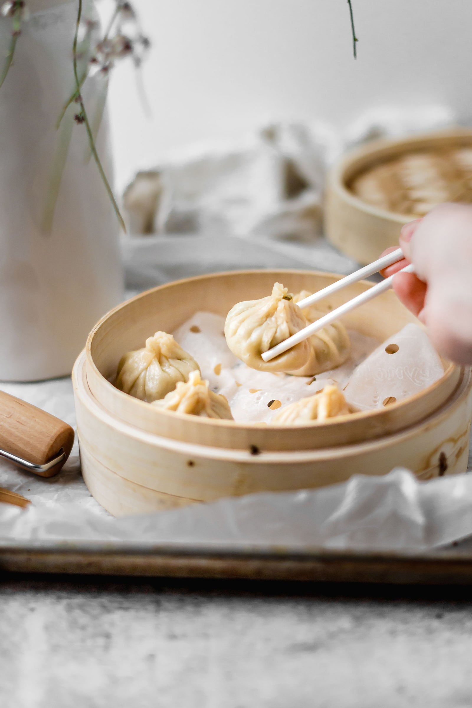 Lifting a xiao long bao dumpling out of bamboo steamer