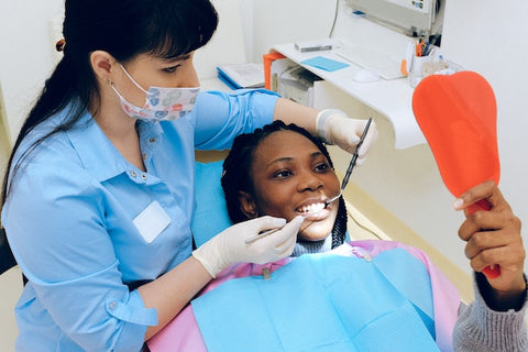 woman looking at teeth in mirror with dentist