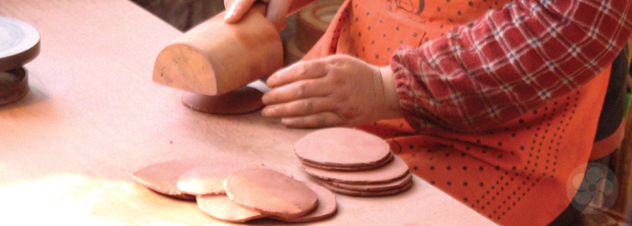 round patties of clay are flattened by hand with a wooden mallet in this yixing workshop