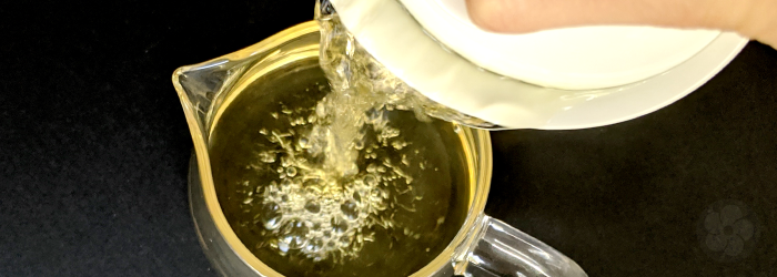 tea poured into a glass server from a white gaiwan