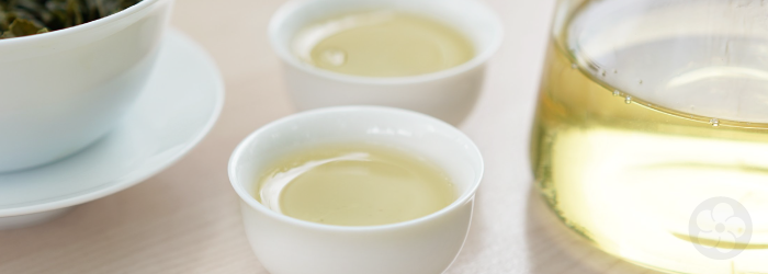 porcelain tasting cups and glass pitcher containing a brew of lightly oxidized oolong tea