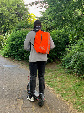man on electric scooter with high visibility backpack cover