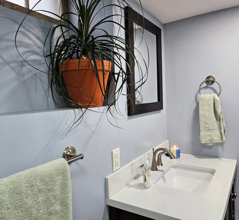 Satin Nickel Portland Bath Hardware in a light blue bathroom with light green bath towels and glowing candle.