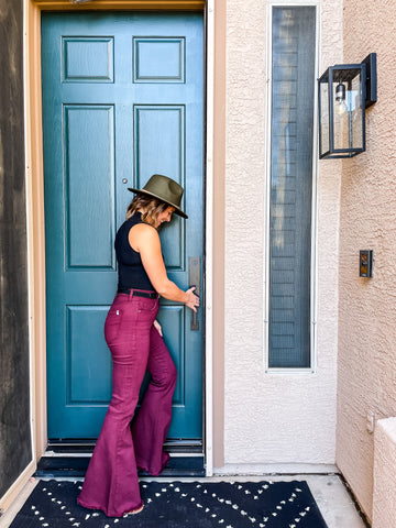 Women Opening a Matte Black Munich Handleset on a Teal Door