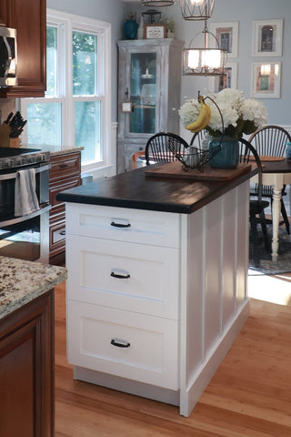 Matte black cabinet pulls on a white island in an airy kitchen