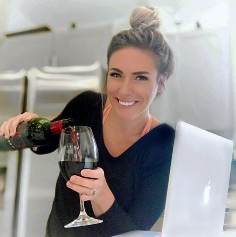 Woman pouring a glass of red wine, wearing the top knot hairstyle created with PONY-O hair accessories