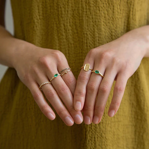 hands wearing gold and emerald rings