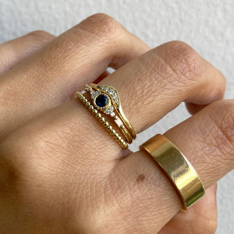 fingers wearing gold and sapphire jewelry