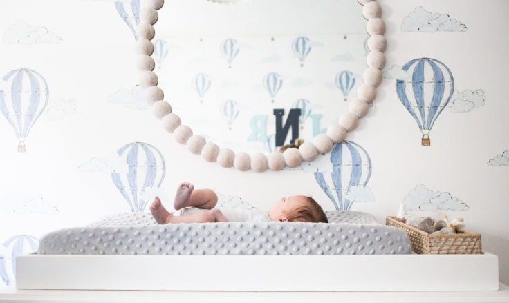 Balloon themed baby boy's nursery with balloon wallpaper and wooden mirror.