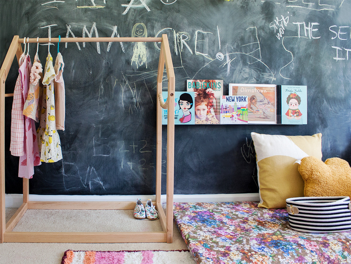 Kids room with chalkboard wall and colorful area rugs and wooden clothing rack