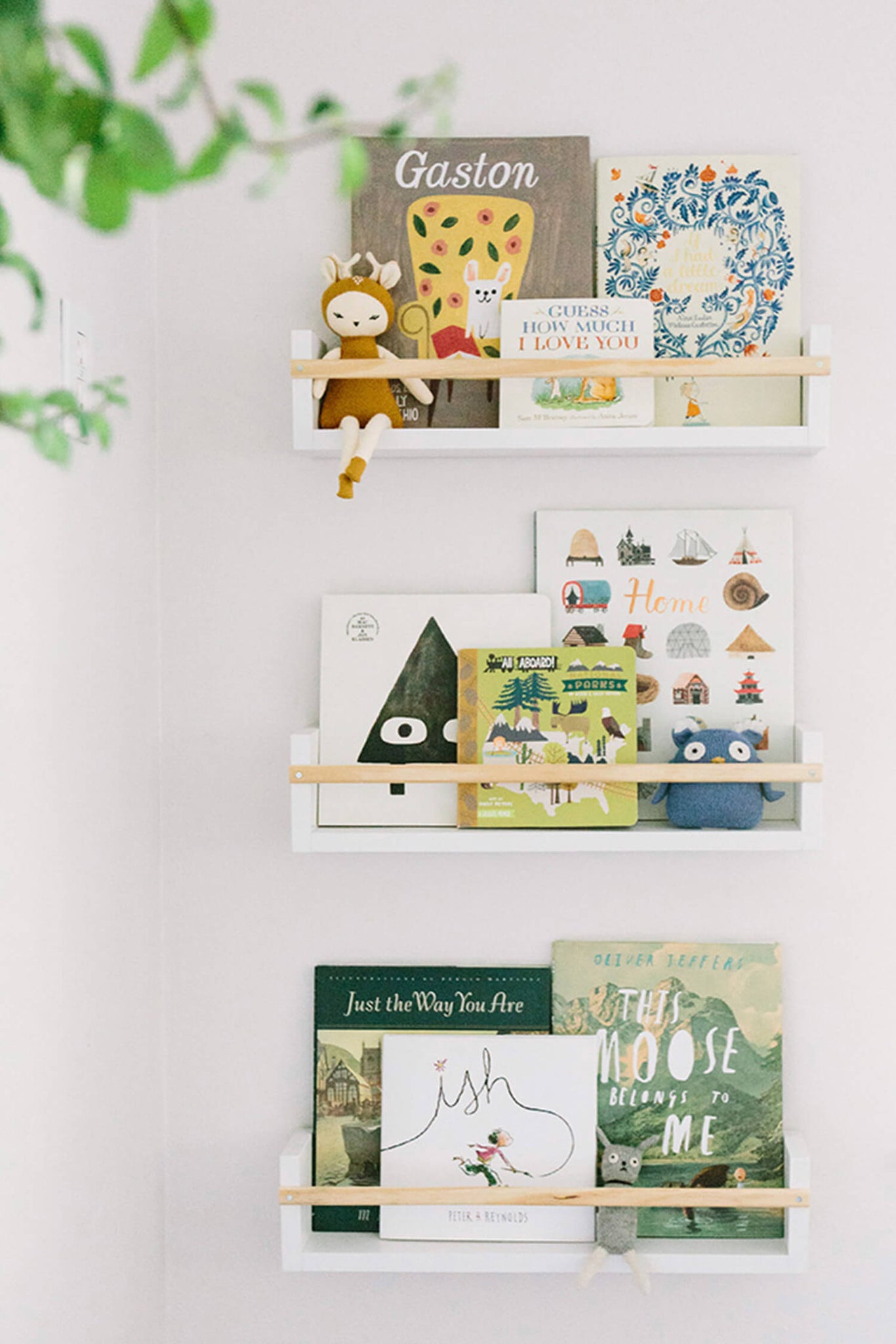 Nursery floating shelves with colorful books, art display.