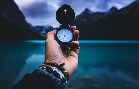 Person holding a compass near a river