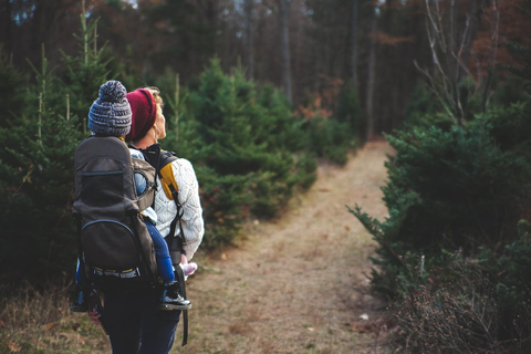 Woman carrying a baby with her backpack on a hiking trail