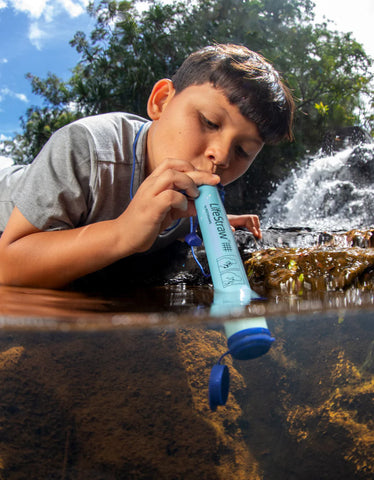 LifeStraw-personal_water filtration used by young boy half in a pond at Kauai - picture by Adam Barker