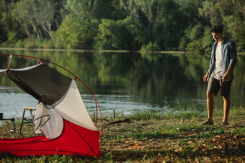 Traveler on river shore against tent during summer journey