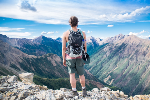 man wearing a hiking backpack in front of mountains