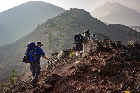 A group of people carrying backpacks and hiking on a mountainous trail