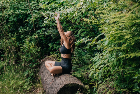 a person doing stretching sitting on a tree trunk.