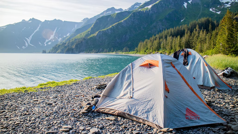 Two camping tents next to a lake