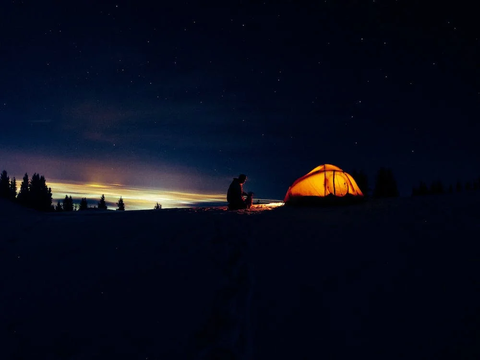 A person setting up a tent at night 