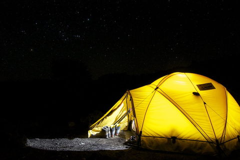 A lighted yellow camp at night 