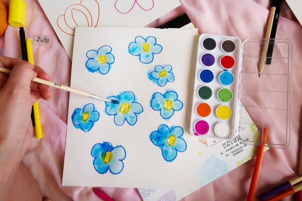 painting in the marker drawn flowers in blue with watercolor paints