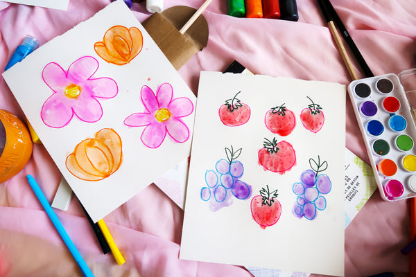 painting in the marker drawn flowers and fruit with watercolor paints
