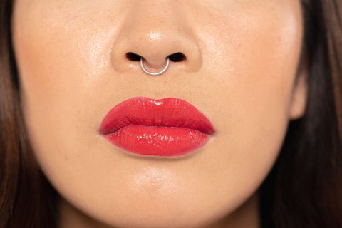 Close up of model's lips wearing vegan red lip gloss for classic French look makeup