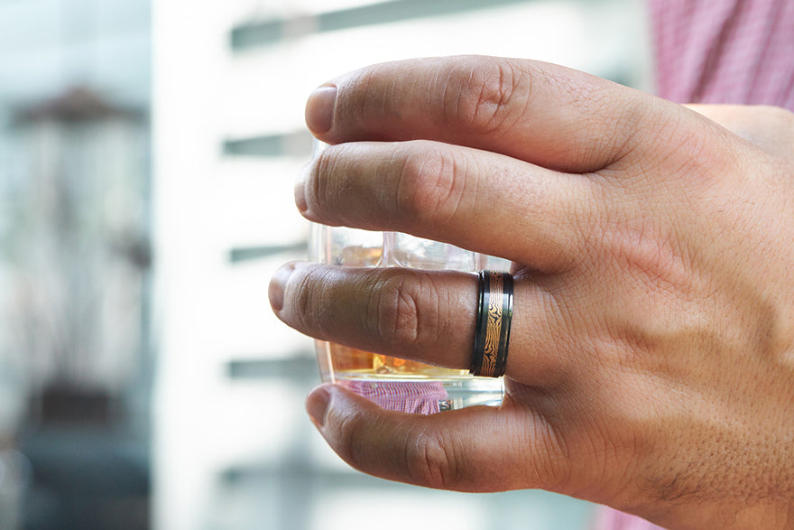 man wearing ring holding a glass