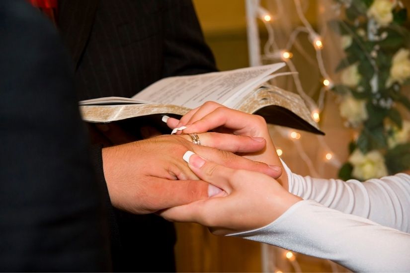 Premium Photo | Close-up of the hand of the groom puts a wedding ring on  the brides finger, the ceremony on the street, selective focus