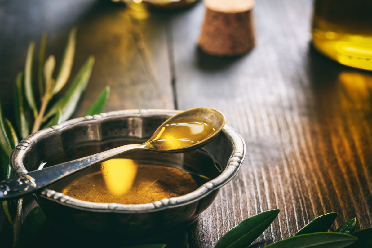 Small bowl of cold-pressed olive oil on wooden table