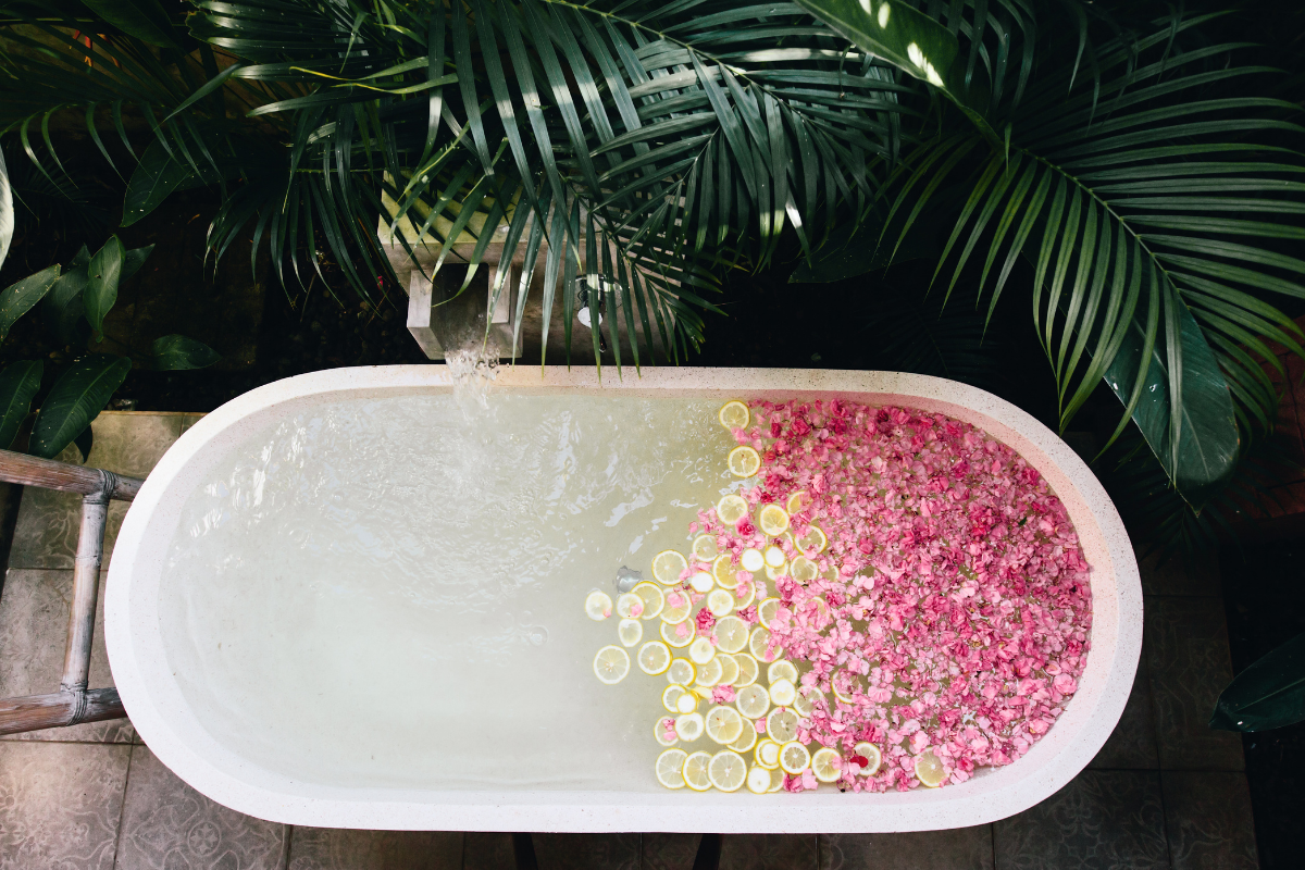 bath rub from above filled with rose petals and lemon