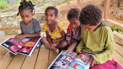 Girls learning to read in PNG with Kingstone comics