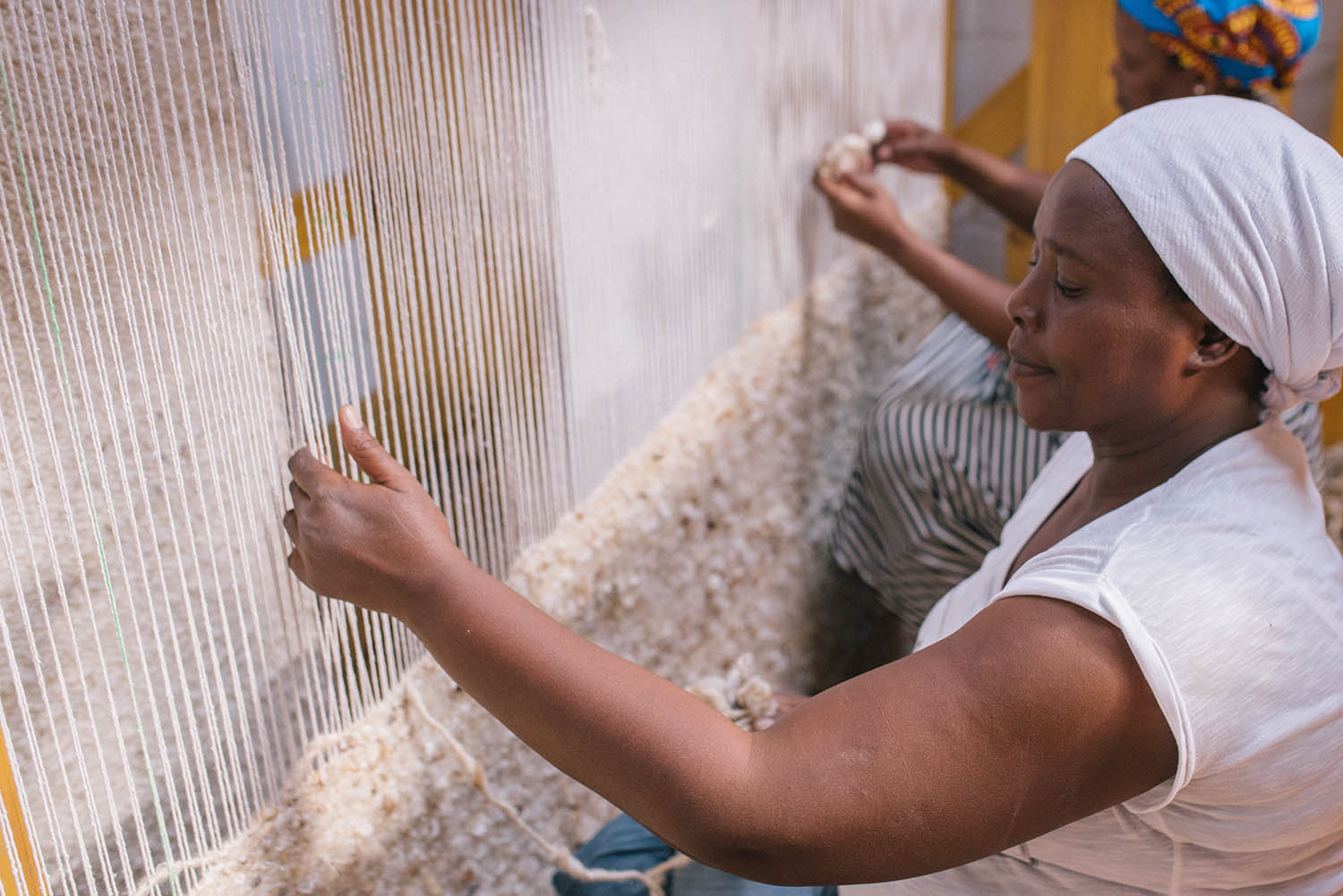 A Coral & Hive weaver working on a loom to create a custom rug. Coral & Hive rugs are available at Sarza home goods, furniture and rug store