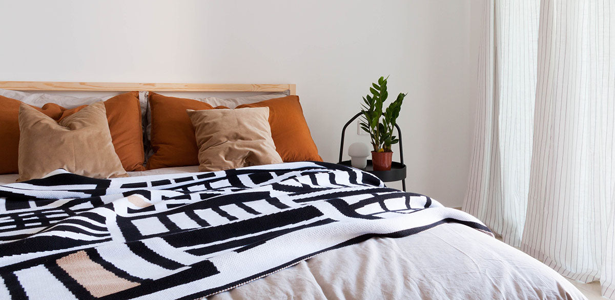 A Something Good Studio blanket styled on a bed.Something Good home décor products are available at Sarza home goods and furniture store in Rye New York.