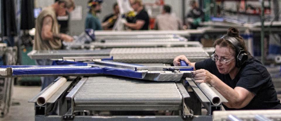 A DiamondBack employee masks a truck bed cover before application of Rugged Black