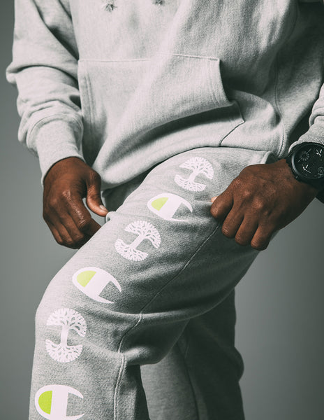 On grey fleece, highlighter green and white, OAKLAND and Champion logo, grey sweatpants.