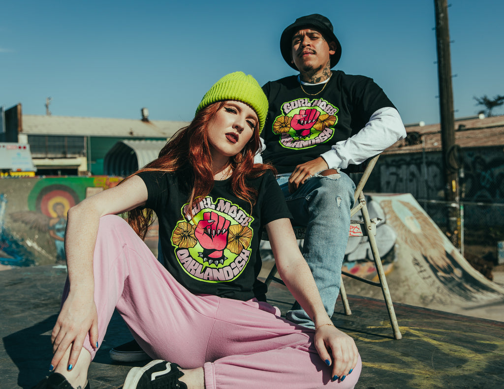 Girl and guy wearing black tee with design with fist and flowers.