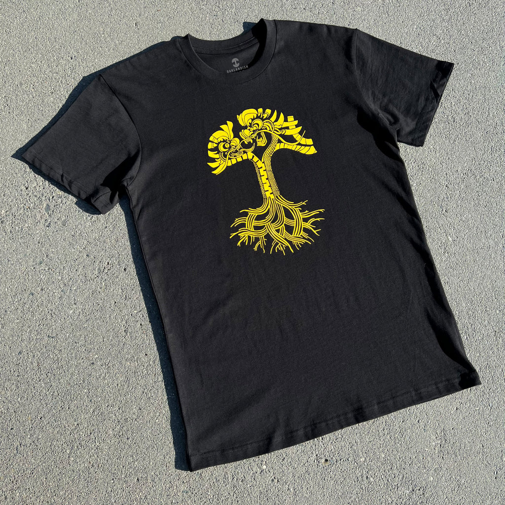 Black t-shirt lying on asphalt with gold Dragon Power graphic design.