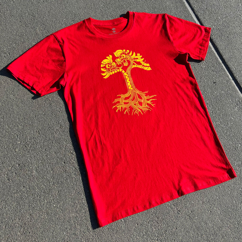 Red t-shirt laying on asphalt with gold Dragon Flower design.